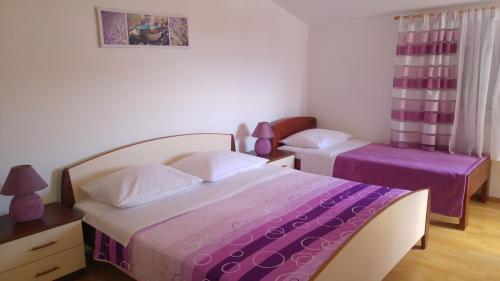 a bedroom with two beds with purple sheets at Apartments Tonći and Iris in Primošten