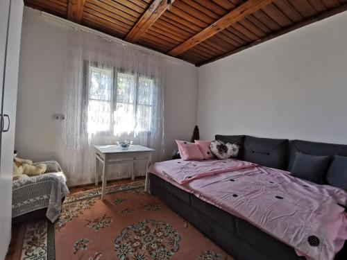 a bedroom with a bed and a table and a window at Konak Mileva in Sjenica