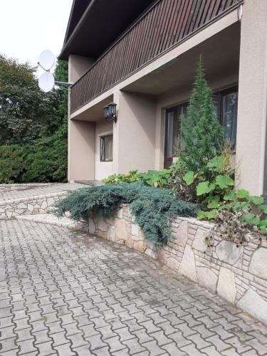 a house with a stone retaining wall next to a street at IOMAN HAUS in Ikšķile