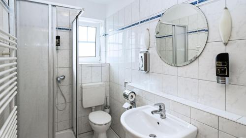 La salle de bains est pourvue de toilettes, d'un lavabo et d'un miroir. dans l'établissement Hotel vom Land zum Meer, à Jork