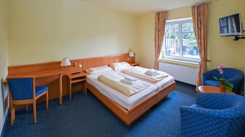 a bedroom with a bed and a desk and two chairs at Hotel vom Land zum Meer in Jork