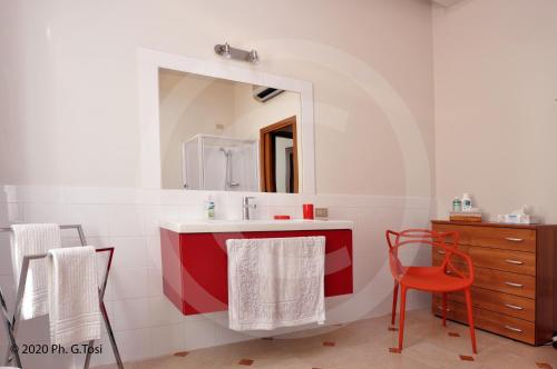 bagno con specchio e lavandino rosso e bianco di A.A.A. Armonie B&B a Mantova