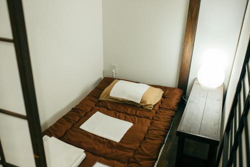 Cama pequeña en habitación pequeña con mesa en Guest House KuKu, en Niigata
