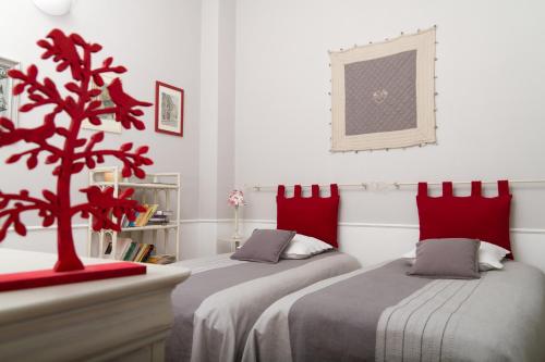 a bedroom with two beds with red pillows and a tree at Appartement Rennel in Nancy