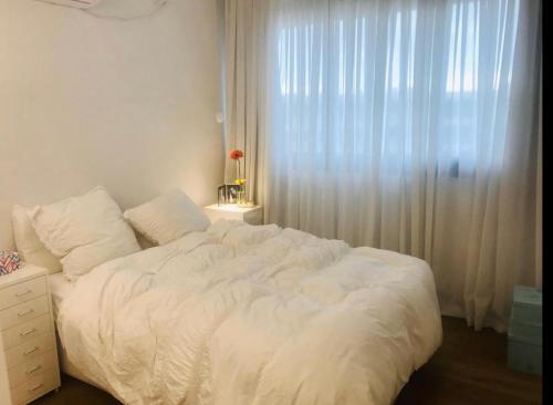 凱撒利亞的住宿－מיני פנטהאוס מול ים קיסריה，卧室内的一张白色床,设有窗户