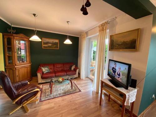 a living room with a red couch and a tv at Noclegi Dobry Kwadrat in Bodzentyn