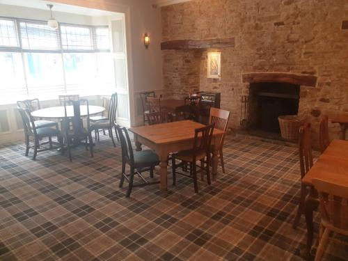 a dining room with tables and chairs and a fireplace at The Black Swan Inn in Pickering