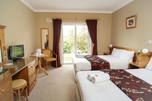 a hotel room with two beds and a television at Ardilaun Guesthouse Self Catering in Ennis