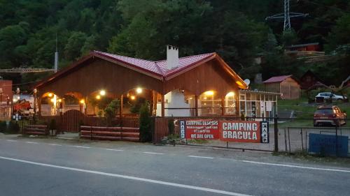 a building with lights on it on the side of the road at CABANUTE si CAMPING DRACULA in Căpăţîneni-Pămînteni