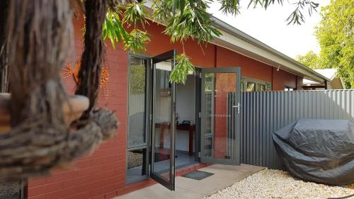 a red house with glass doors and a fence at Red Ochre - Large Apartment with Private Courtyard in Port Pirie
