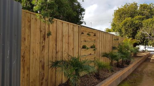 a wooden fence with plants in front of it at Red Ochre - Large Apartment with Private Courtyard in Port Pirie