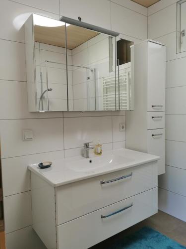a white bathroom with a sink and a mirror at Ferienwohnung auf der Scheibe in Bezau