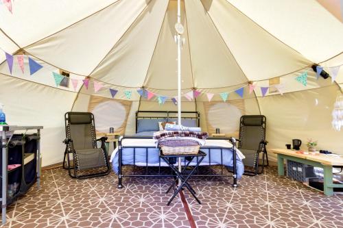 Little Hautbois的住宿－Pitch Perfect Glamping Norfolk，帐篷内的卧室,配有一张床和两把椅子