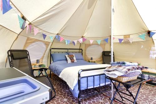 Pitch Perfect Glamping Norfolk في Little Hautbois: غرفة بسرير في خيمة
