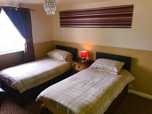 two beds in a room with a window and a lamp at Spalite Hotel in Gloucester