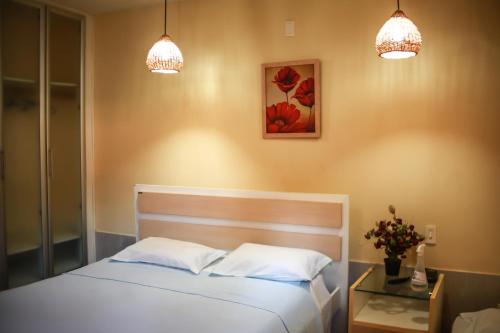 a bedroom with a bed with two lights and a table at Pousada Corais do Sul in Pipa
