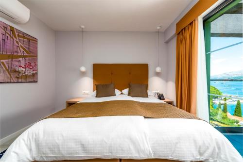 a bedroom with a large bed and a large window at Hotel Seventh in Cavtat