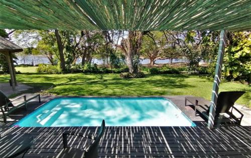 a swimming pool in a yard with chairs and a tent at The Maun Studios in Maun