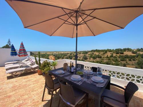 une table à manger avec un parasol sur un balcon dans l'établissement Casa Pura Vida - fantastic sea view, à Pêra