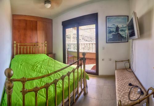 um quarto com uma cama com um edredão verde em Casa Playa De Guainos em Adra