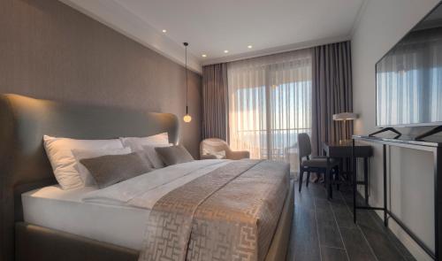 a hotel room with a large bed and a desk at Vivid Blue Serenity Resort in Sveti Stefan
