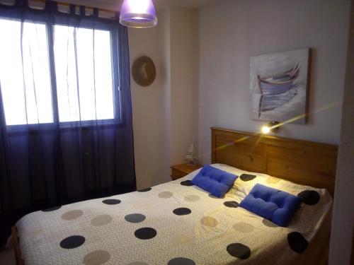 a bedroom with a bed with blue pillows and a window at Preciosos atardeceres san marcos in Icod de los Vinos