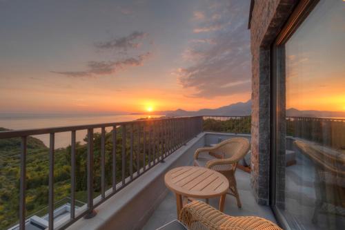 a balcony with two chairs and a sunset at Vivid Blue Serenity Resort in Sveti Stefan