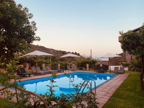 una piscina con sillas y sombrillas en un complejo en Villa Le Gemelle Dell'Alcantara, en Motta Camastra
