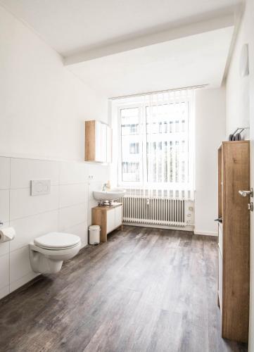 a white bathroom with a toilet and a sink at Central Apartments Aalen in Aalen