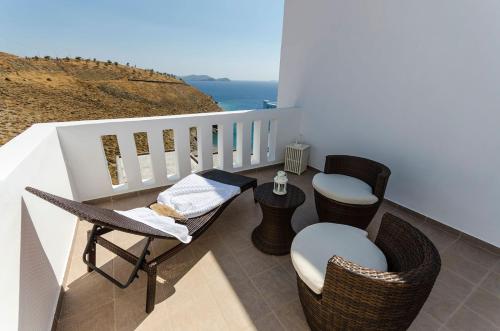 a balcony with chairs and a table and the ocean at Votsalo in Astypalaia