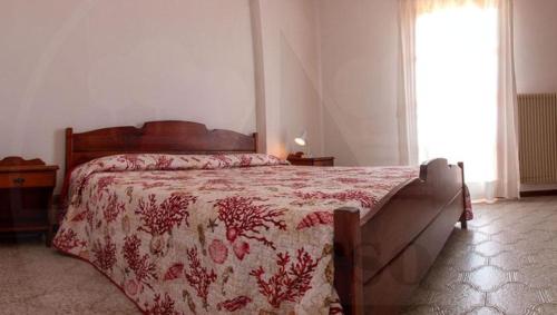 a bedroom with a bed with a red comforter and a window at VILLA ROSA in Duna Verde
