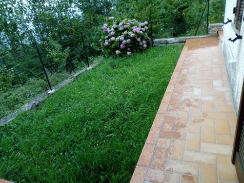 a garden with green grass and a fence and flowers at CASA ELISA (casa della nonna) in Montereggio