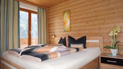 een slaapkamer met een groot bed in een houten muur bij Ferienwohnung Gundolf - Astner in Wenns