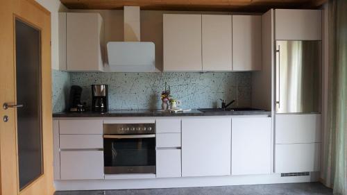 een keuken met witte kasten en een oven bij Ferienwohnung Gundolf - Astner in Wenns