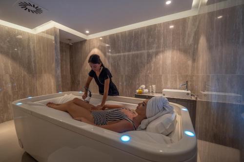 two women laying in a bath tub in a bathroom at Vivid Blue Serenity Resort in Sveti Stefan