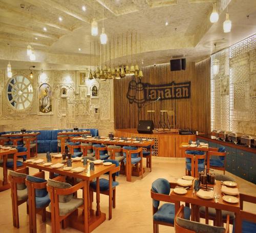a restaurant with wooden tables and blue chairs at Ramee Royal Resort & Spa - Udaipur in Udaipur