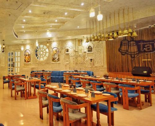 a restaurant with wooden tables and blue chairs at Ramee Royal Resort & Spa - Udaipur in Udaipur