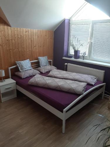 ein Schlafzimmer mit einem großen Bett mit violetter Bettwäsche und einem Fenster in der Unterkunft Útulný apartmán in Veselí nad Moravou