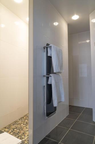 La salle de bains est pourvue de serviettes blanches accrochées au mur. dans l'établissement Residence Le Silex, à Sancerre