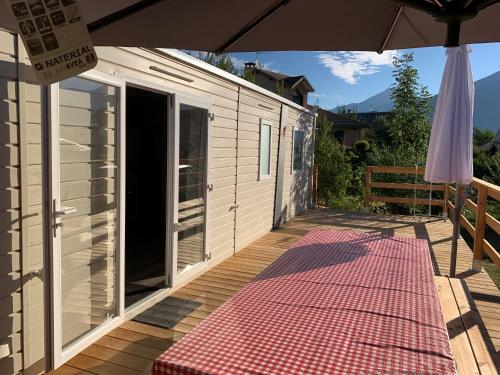 eine Terrasse mit einem Sonnenschirm und einem rosa Teppich in der Unterkunft Mobilhome 3 étoiles in Embrun