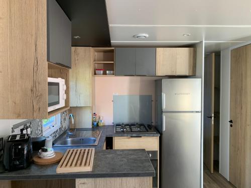 a kitchen with a white refrigerator and a sink at Mobilhome 3 étoiles in Embrun