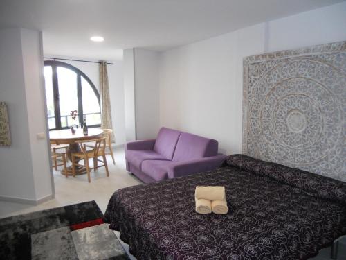 プラヤ・デ・ラス・アメリカスにあるPARQUE SANTIAGO - PLAYA LAS AMERICASのベッドルーム(紫色のベッド1台、紫色のソファ付)