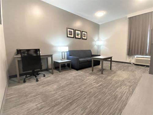 a living room with a couch and a desk and a chair at Baymont by Wyndham Lafayette - Purdue University in Lafayette