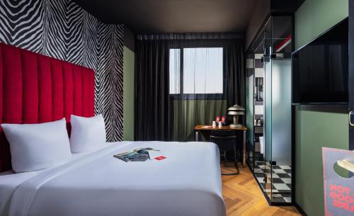 Dave Downtown, a member of Brown Hotels في تل أبيب: غرفة نوم مع سرير أبيض مع اللوح الأمامي الأحمر