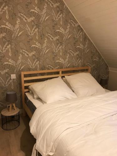 - une chambre dotée d'un lit avec des draps blancs et du papier peint floral dans l'établissement ty_yaouen maison de vacances, à Carantec