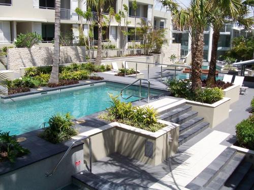 a swimming pool with stairs and palm trees in a building at The Beach Cabarita in Cabarita Beach