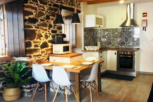 a kitchen with a wooden table and white chairs at My Historic House 2 in Bragança
