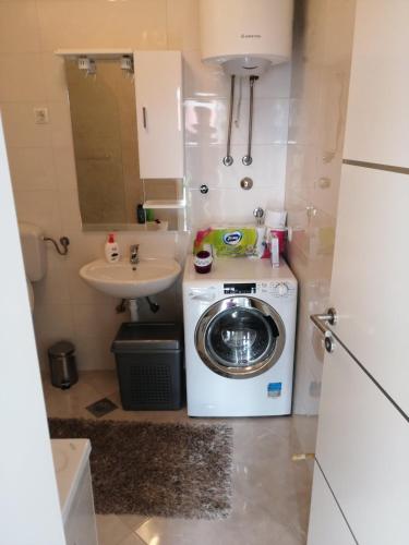 a small bathroom with a washing machine and a sink at Sun garden apartment in Trebinje