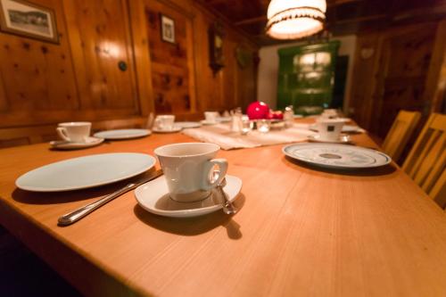 a wooden table with plates and coffee cups on it at Pension der Steinbock - das 300 Jahre alte Bauernhaus - TIROL in Sankt Anton am Arlberg