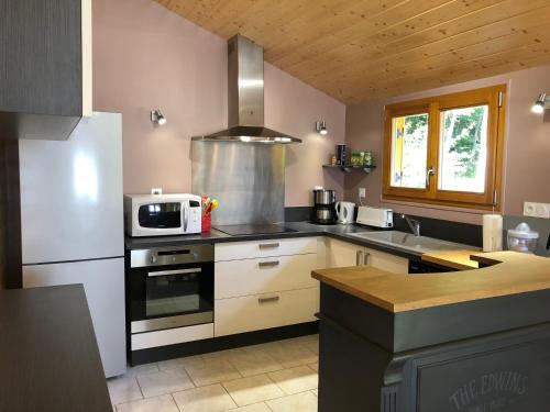 a kitchen with a stove and a microwave at Chalet O FIL DE L EAU , jusque 6 pers , à XONRUPT LONGEMER in Xonrupt-Longemer